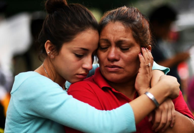 Relatives of people who are presumed still buried under the rubble from a building toppled by the quake comfort each other whilst they wait for any news