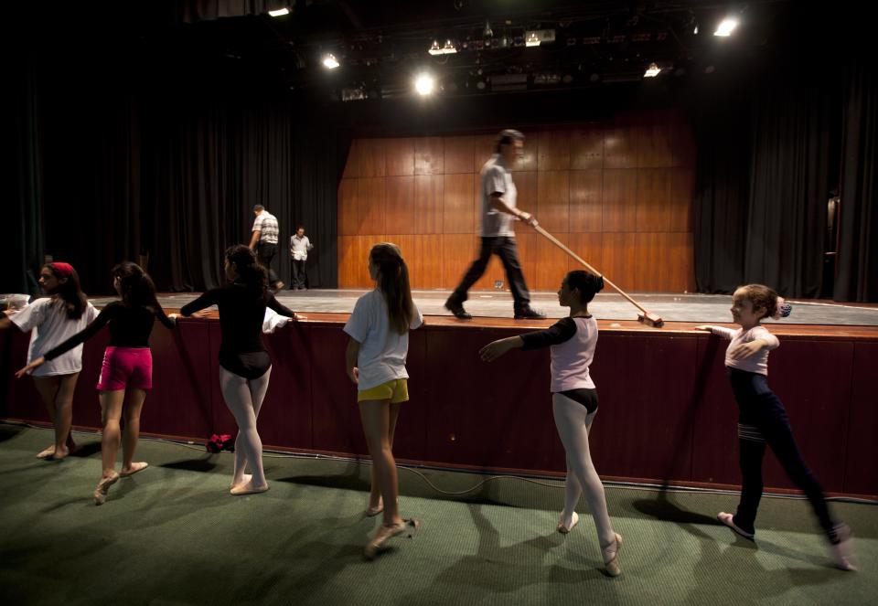 In this Sept. 3, 2012 photo, dancers practice for a competition between ballet schools as workers prepare the dance stage inside the National Museum in Lima, Peru. Nearly 100 girls and boys from Colombia, Venezuela, Chile, France and Peru are submitting themselves to a week-long competition hoping to win medals from Peru's national ballet school _ and perhaps a grant to study in Miami. (AP Photo/Martin Mejia)