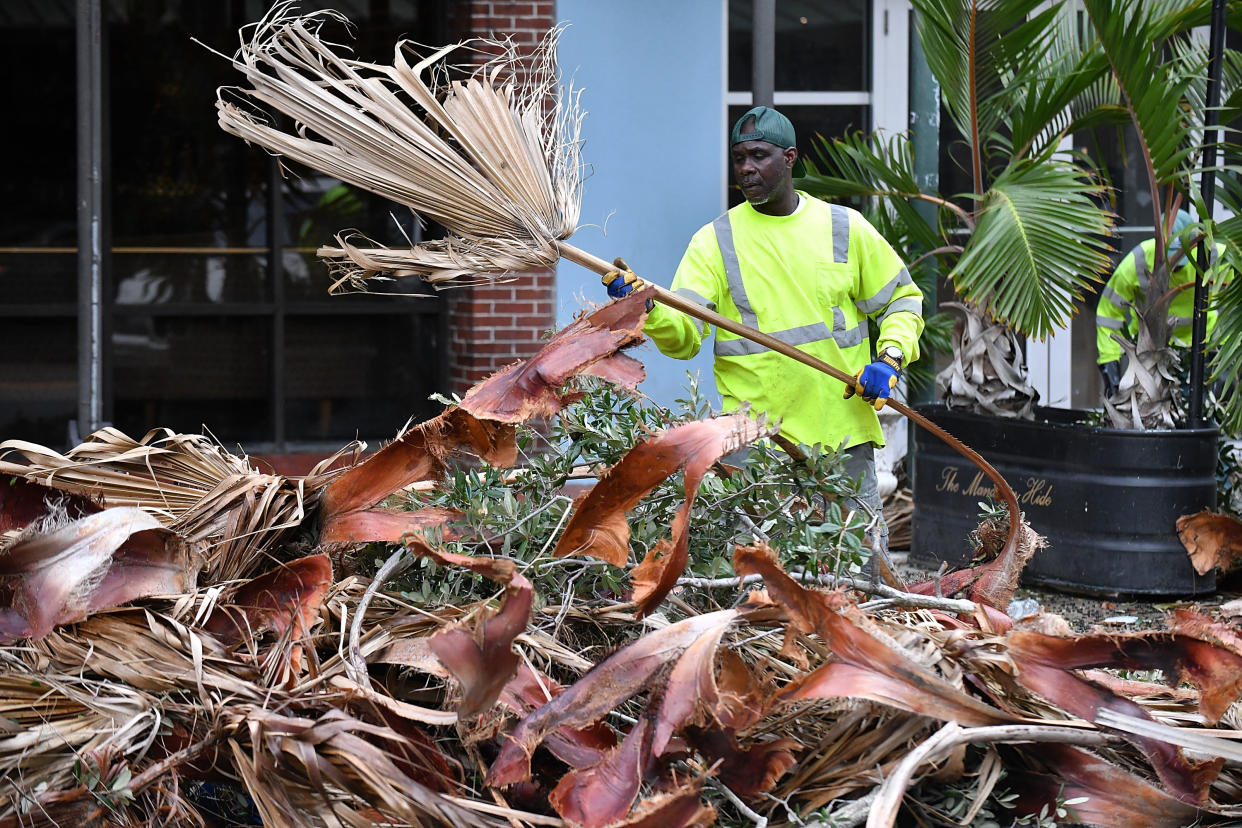 A worker clears debris and palm fronds in downtown St. Petersburg, Fla., following Hurricane Ian.