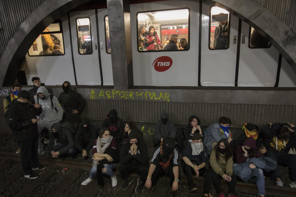 Demonstrators block a train rail at the subway, during a general strike in Catalonia, Spain, Thursday, Feb. 21, 2019. Protesters backing Catalonia's secession from Spain clashed with police and blocked major roads and train tracks across the northeastern region on Thursday during a strike called to protest the trial of a dozen separatist leaders. (AP Photo/Emilio Morenatti)