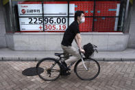 A man wearing a face mask to help curb the spread of the coronavirus rides a bicycle near an electronic stock board showing Japan's Nikkei 225 index at a securities firm in Tokyo Monday, July 13, 2020. Asian shares rose Monday, cheered by recent upbeat projections on a global rebound tempered with worries about disappointment that could follow. (AP Photo/Eugene Hoshiko)