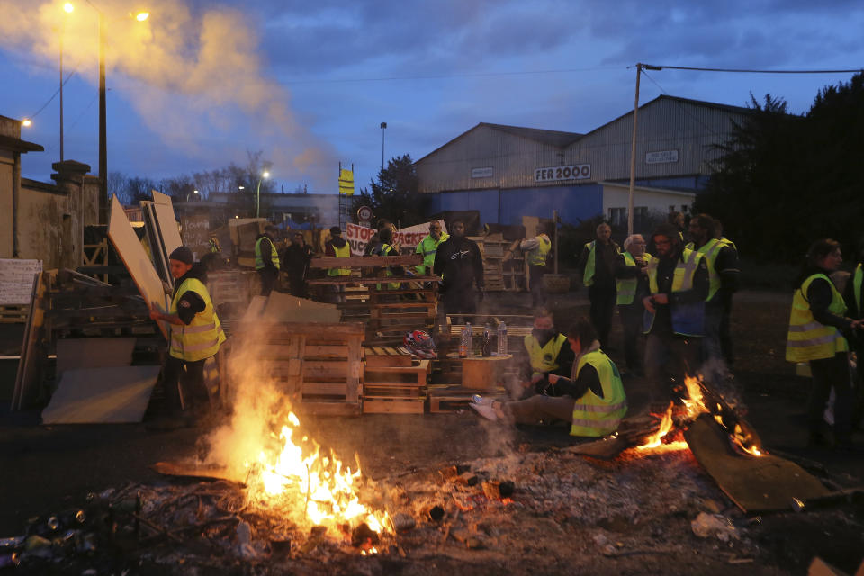 FILE - In this Tuesday, Dec. 5, 2018 file photo, demonstrators stand at a makeshift barricade set up by the "yellow jackets" protesters to block the entrance of a fuel depot in Le Mans, western France. Even proponents of carbon taxes acknowledge that an increase in fuel taxes can disproportionally hurt low-income people. Energy costs make up a larger portion of their overall expenses, so a fuel price increase eats up more of their paycheck and leaves with less to spend. (AP Photo/David Vincent)