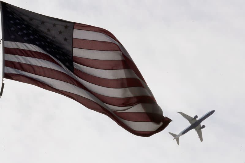 A Delta Airlines flight takes off past a U.S. flag in Boston