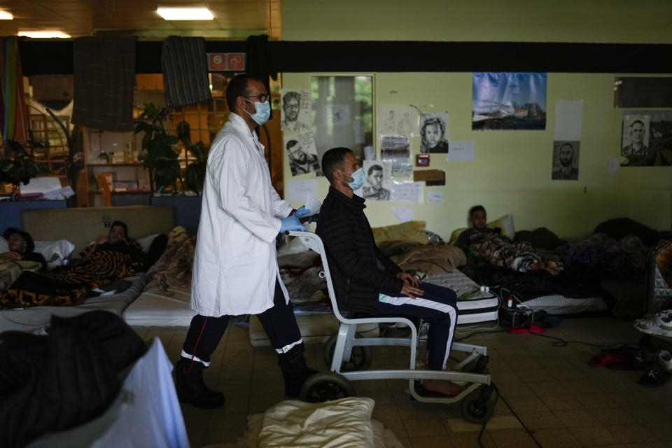 A firefighter transfers a man man on hunger strike to a hospital as he occupies with others a big room of the ULB Francophone university in Brussels, Tuesday, June 29, 2021. More than two hundreds of migrants without official papers and who have been occupying a church and two buildings of two Brussels universities since last February, began a hunger strike on 23 May to draw the attention of Brussels authorities to their plight. (AP Photo/Francisco Seco)