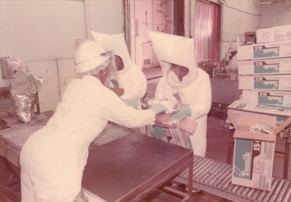 Thiokol plant workers dressed from head to toe, including masks to avoid inhaling chemicals and gases. Circa 1960s.