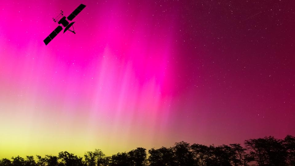  The silhouette of a satellite against a colorful aurora in the sky. 