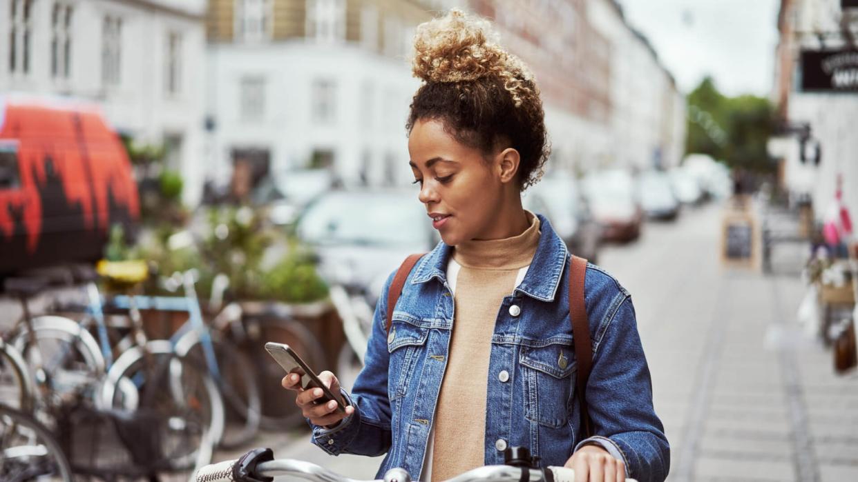 Shot of an attractive young woman using her cellphone while out cycling through the city.