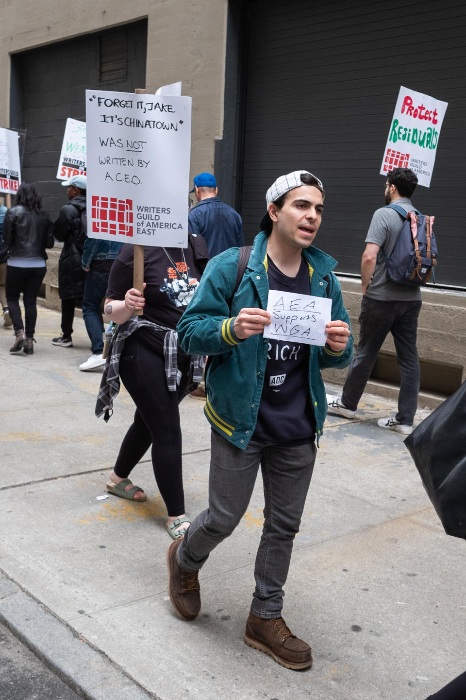 man walks down the street holding sign at WGA strike