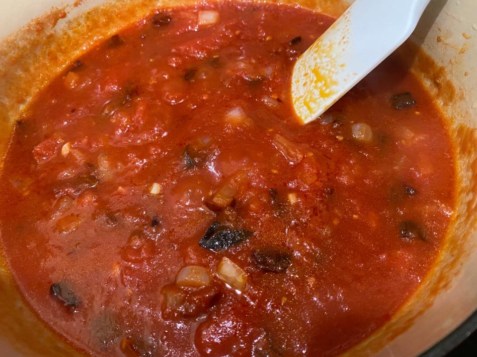 A red pepper sauce is stirred in a pot.