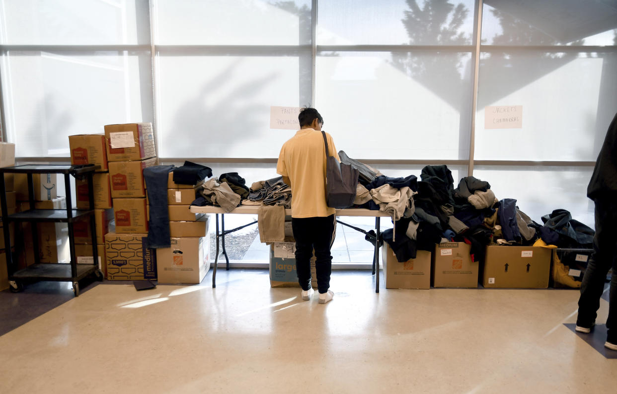 A migrant looks through donated clothes at a makeshift shelter in Denver on Friday, Jan. 6, 2023. Over the past month, nearly 4,000 immigrants, almost all Venezuelans, have arrived unannounced in the frigid city, with nowhere to stay and sometimes wearing T-shirts and flip-flops. In response, Denver converted three recreation centers into emergency shelters for migrants and paid for families with children to stay at hotels, allocating $3 million to deal with the influx. (AP Photo/Thomas Peipert)