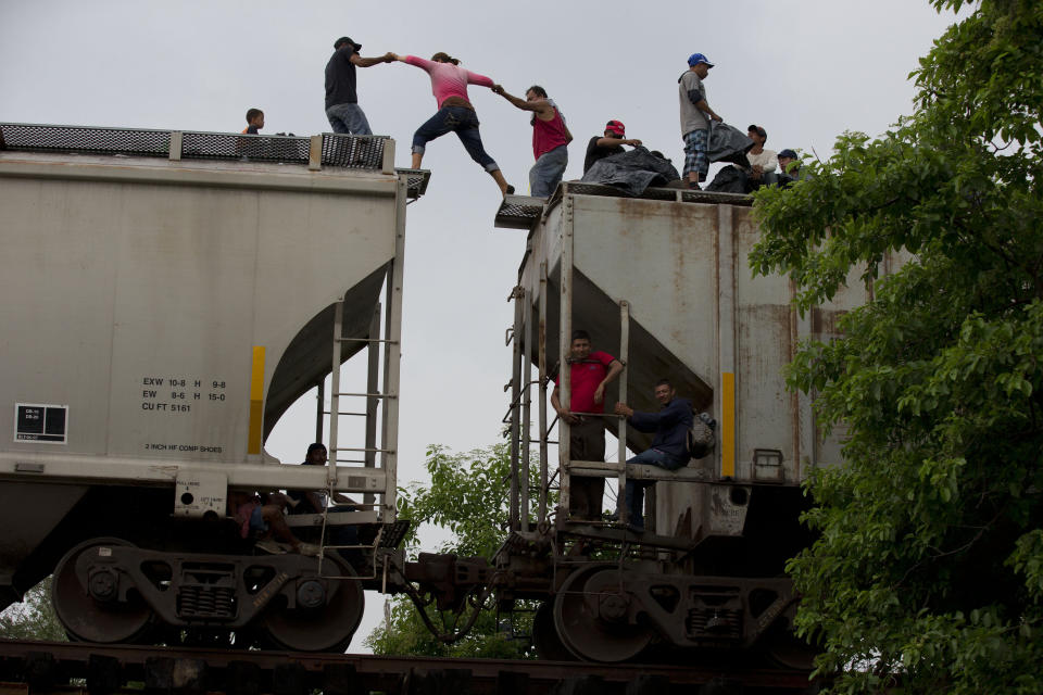 FILE - In this June 20, 2014 file photo, a woman is helped from one boxcar to another, as Central American migrants wait atop the train they are riding north, hours after it suffered a minor derailment in a remote wooded area outside Reforma de Pineda, Chiapas state, Mexico. Many migrants who say they are fleeing criminal violence generally are not eligible for political asylum, which is reserved for groups persecuted for their beliefs or identities. U.N. officials say there is no way of forcing the U.S. and Mexico to accept Central Americans as refugees, but a broad-based change in terminology could bring pressure on the two countries to do more. (AP Photo/Rebecca Blackwell, File)