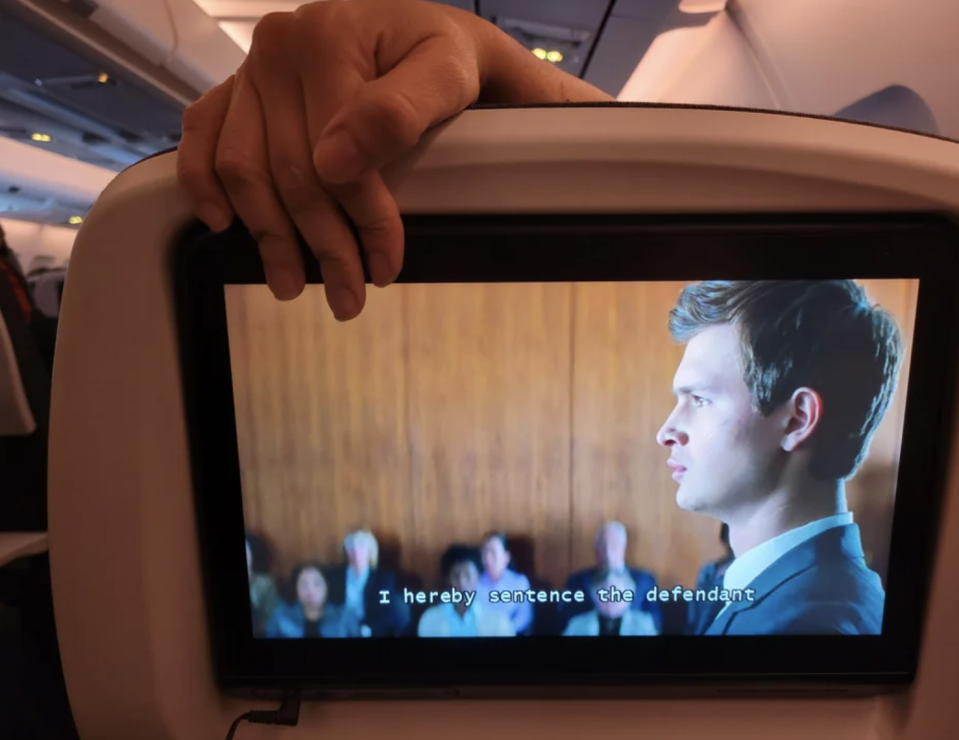 someone's hand blocking someone else's screen on a plane