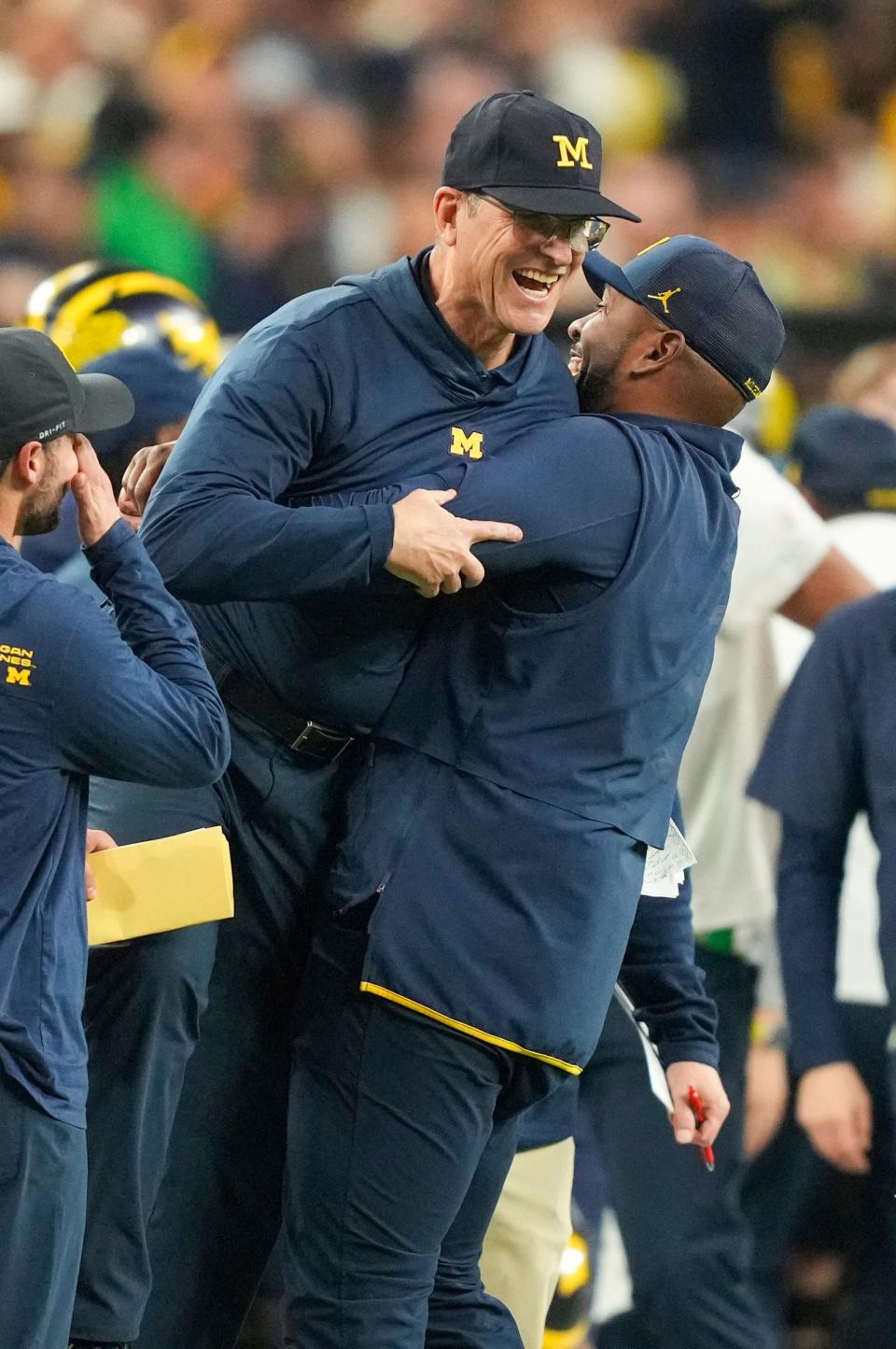 Michigan offensive coordinator Sherrone Moore picks up head coach Jim Harbaugh after they won the College Football Playoff national championship game against Washington at NRG Stadium in Houston, Texas on Monday, Jan. 8, 2024.