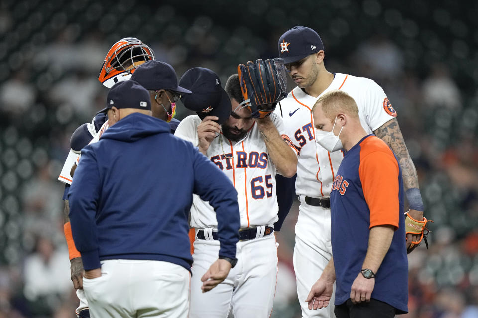 Houston Astros starting pitcher Jose Urquidy (65) removes his cap as he talks with manager Dusty Baker Jr., center left, before leaving the baseball game during the fourth inning against the Los Angeles Angels Wednesday, May 12, 2021, in Houston. (AP Photo/David J. Phillip)