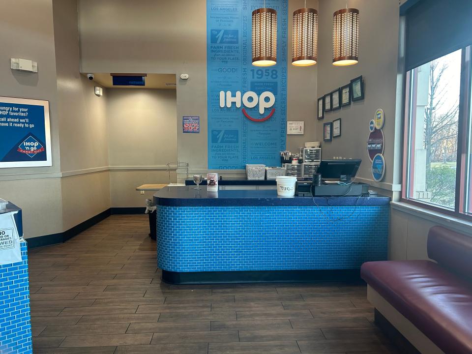 Front host area at IHOP. The room has a bright-blue desk with a computer and the IHOP logo on a wall in the background