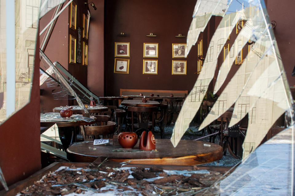 Shards of plate glass frame the damage caused by shelling in a deserted cafe.