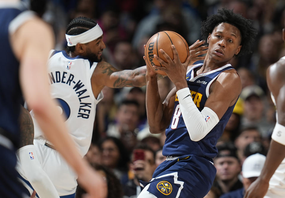 Denver Nuggets forward Peyton Watson, right, pulls in the ball as Minnesota Timberwolves guard Nickeil Alexander-Walker defends during the second half of an NBA basketball game Wednesday, April 10, 2024, in Denver. (AP Photo/David Zalubowski)