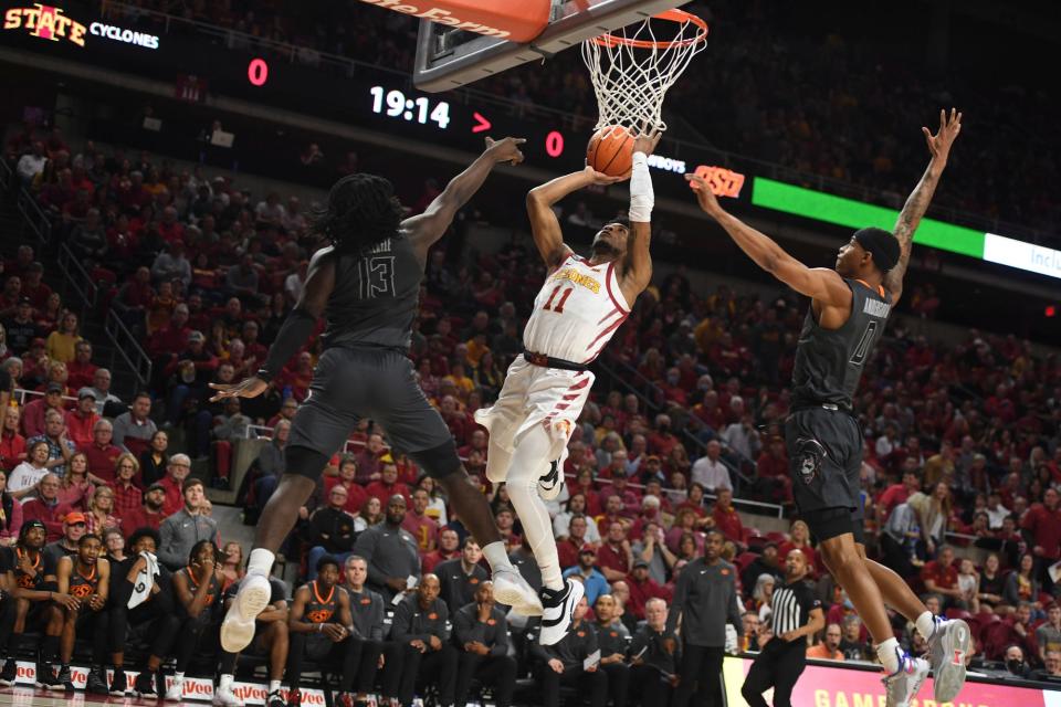 Iowa State star Tyrese Hunter, center, shoots between Oklahoma State's Isaac Likekele, left, and Avery Anderson III. Hunter has transferred to Texas.