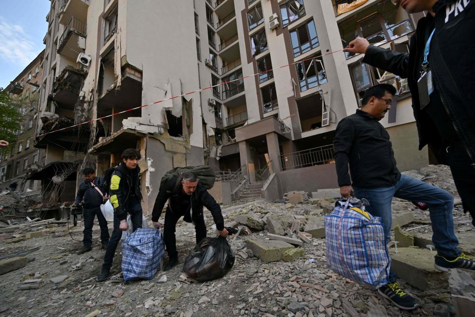 TOPSHOT - Residents carry their belongings as they leave their damaged building following Russian strikes in Kyiv on April 29, 2022, amid Russian invasion of Ukraine. - Russian strikes slammed into Kyiv on April 28, evening as UN Secretary-General Antonio Guterres was visiting.