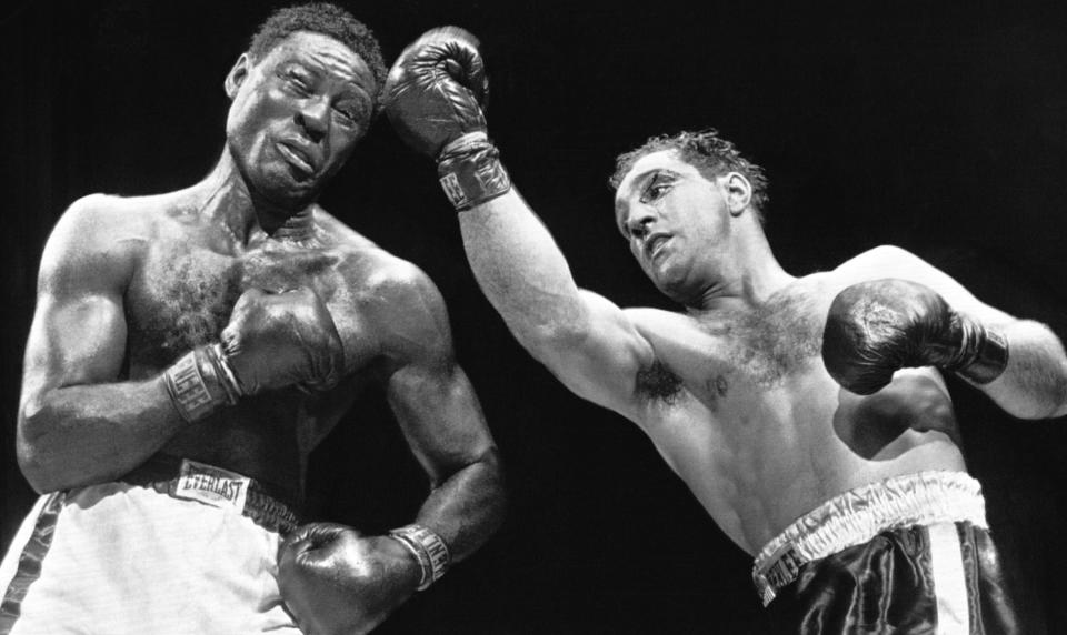 In this June 17, 1954 file photo, heavyweight champion Rocky Marciano strikes challenger Ezzard Charles with a right uppercut in their title bout at Yankee Stadium, New York. Marciano ended his career with a perfect 49-0 record.