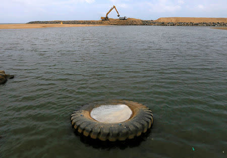 A truck tyre floats in the sea water as an excavator works on land reclamation at "Colombo Port City" construction site, which is backed by Chinese investment, in Colombo, Sri Lanka, August 9, 2016. REUTERS/Dinuka Liyanawatte/File Photo