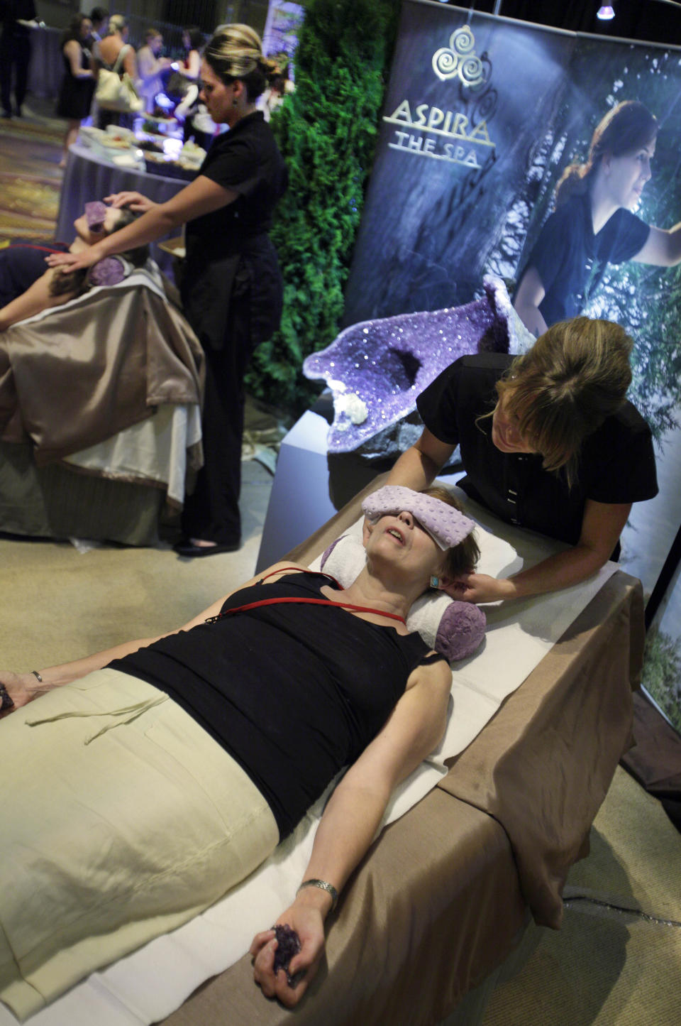 This Aug. 16, 2012 photo shows a woman receiving a spa treatment by a representative of the Aspira Spa, at the Osthoff Resort in Elkhart Lake, Wiisc., in the their booth at the International Spa Association event, in New York. Parties at the spa, treatments for stressed and time-pressed consumers, cross-cultural traditions, and a whole lot of purple _ from lavender-scented treatments to mauve nail polish _ are some of the trends and services that were shown off at the annual International Spa Association meeting held recently in New York. (AP Photo/Richard Drew)