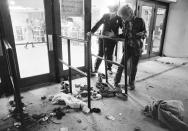 FILE - A security guard and an unidentified man look at an area where several people were killed as they were caught in a surging crowd entering Cincinnati's Riverfront Coliseum for a concert by The Who, Dec. 3, 1979. (AP Photo/Brian Horton, File)