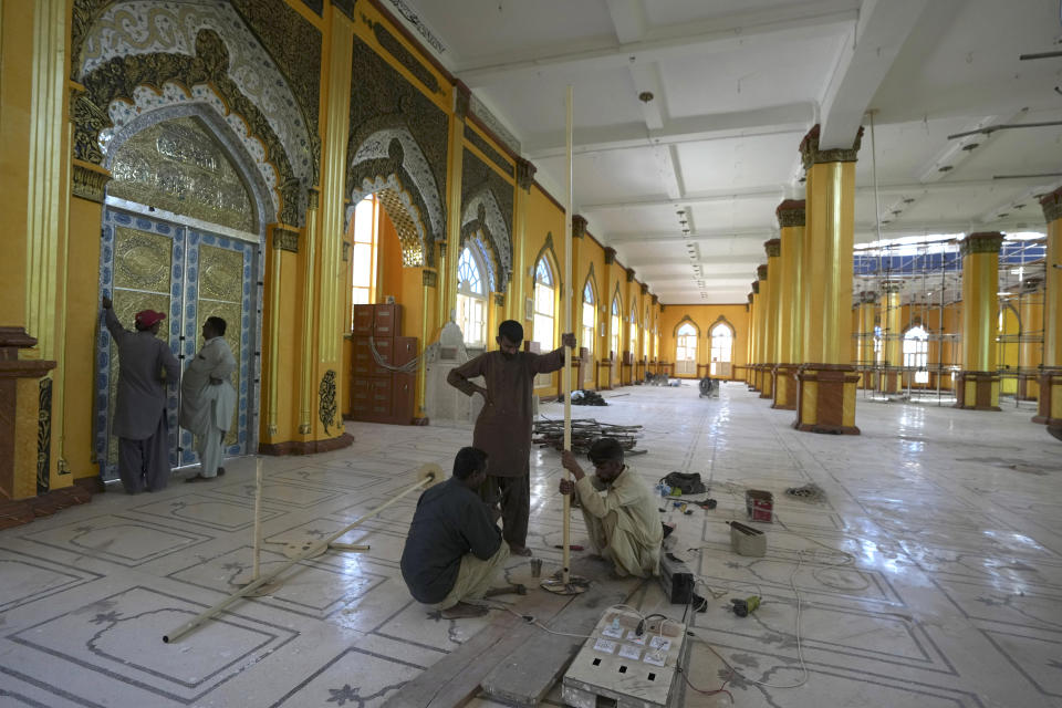 Workers remove a structure after finishing repairing and paint work in a mosque ahead of the upcoming Muslim fasting month of Ramadan, in Karachi, Pakistan, Tuesday, March 21, 2023. Muslims across the world will be observing the Ramadan, when they refrain from eating, drinking and smoking from dawn to dusk. Ramadan is expected to officially begin Thursday or Friday in Pakistan, though the timing depends on the alignment of the moon. (AP Photo/Fareed Khan)