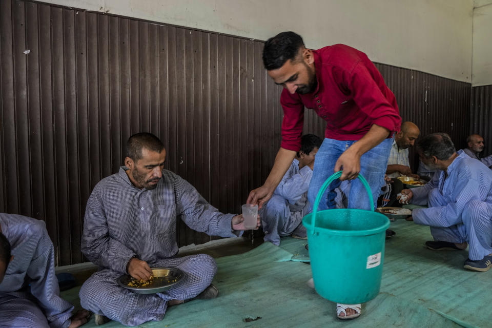 A staff member of a mental health hospital serves drinking water to a patient inside a mental health hospital in Srinagar, Indian controlled Kashmir, Tuesday, Aug 1, 2023. Kashmir's mental healthcare clinics depict invisible scars of decades of violent armed insurrections, brutal counterinsurgency, unparalleled militarization, unfulfilled demands for self-determination have fueled depression and drugs in the disputed region, experts say. (AP Photo/Mukhtar Khan)