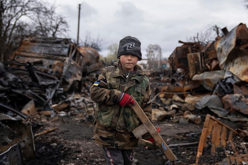 Yehor, 7, stands holding a wooden toy rifle next to destroyed Russian military vehicles near Chernihiv, Ukraine, Sunday, April 17, 2022.