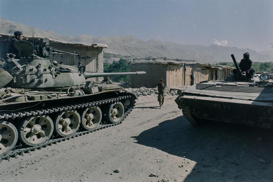 Two tanks are seen in a dry, sandy area.