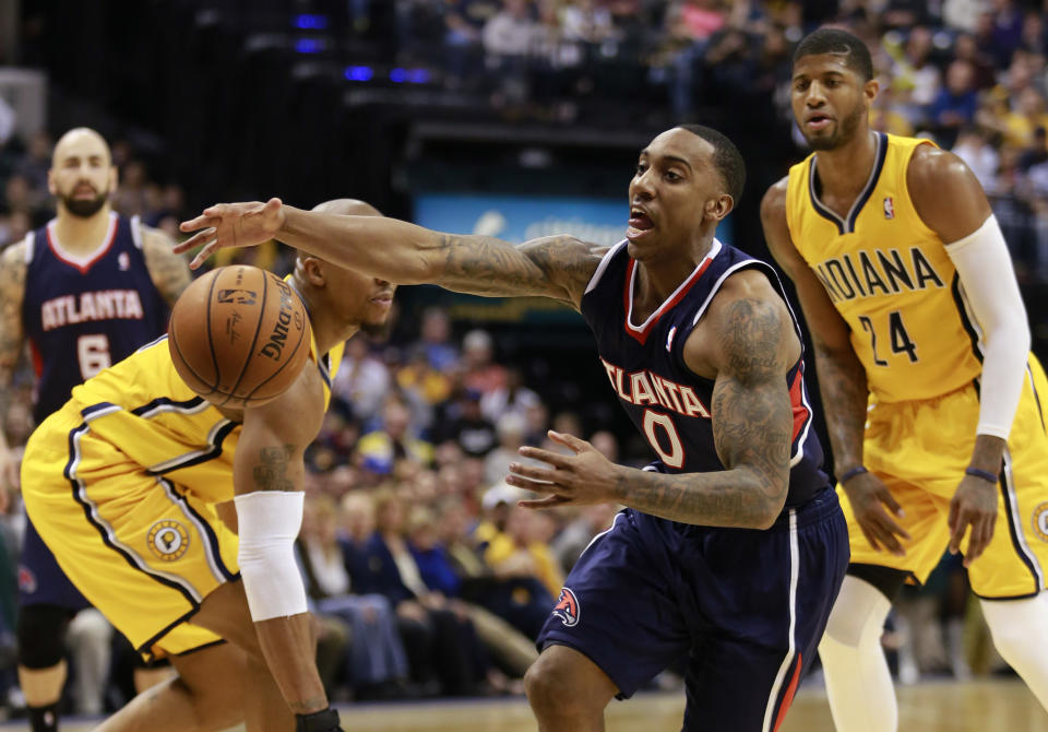 Atlanta Hawks guard Jeff Teague (0) reaches for the basketball after driving between Indiana Pacers forward Paul George, right, and Pacers forward David West in the first half of an NBA basketball game in Indianapolis, Sunday, April 6, 2014. (AP Photo/R Brent Smith)