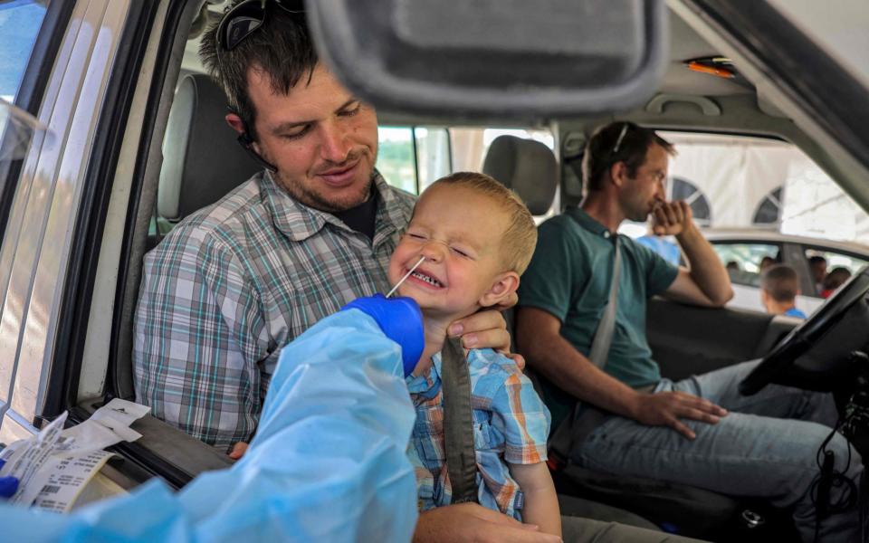 A medic performs a COVID-19 coronavirus swab test on a child in a vehicle at a Home Front command drive-through coronavirus testing complex in Jerusalem  - MENAHEM KAHANA/AFP