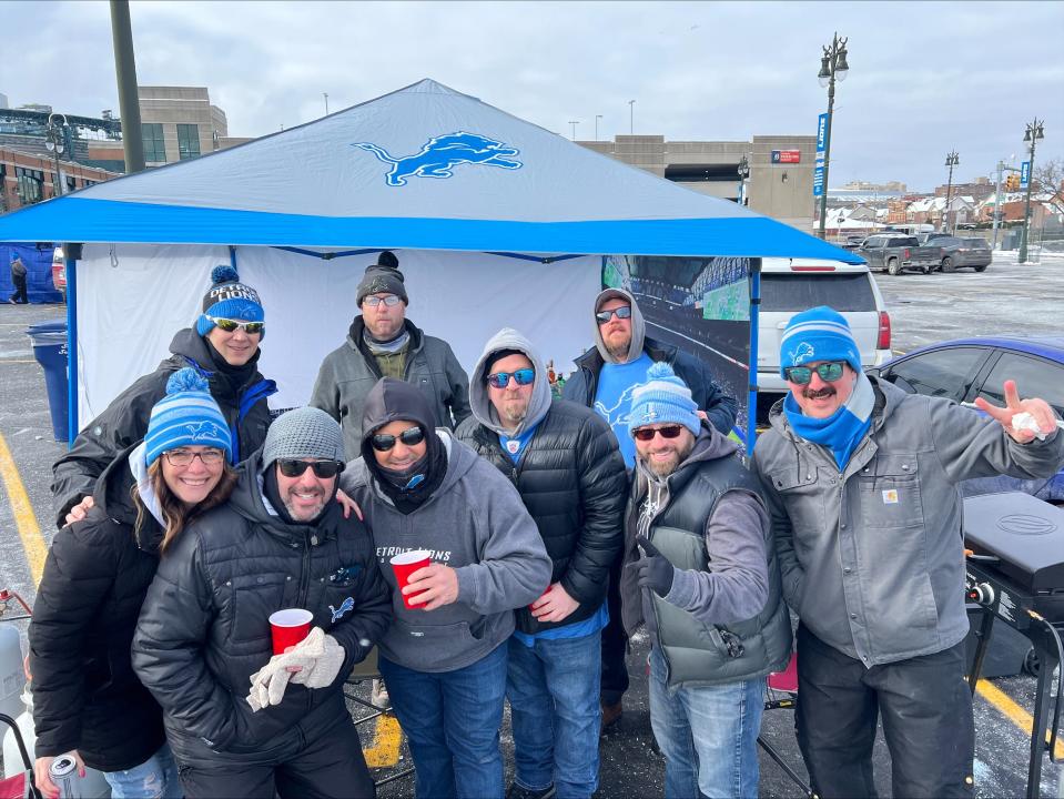 Wearing a black hood and sunglasses, Jason Clinton, 45, of Milford leans on Shelby Berger, 42, of Birmingham as friends gather to tailgate ahead of the Detroit Lions game against the Tampa Bay Buccaneers.
