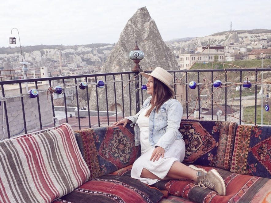 A woman sitting on colorful pillows with a mountain behind her.