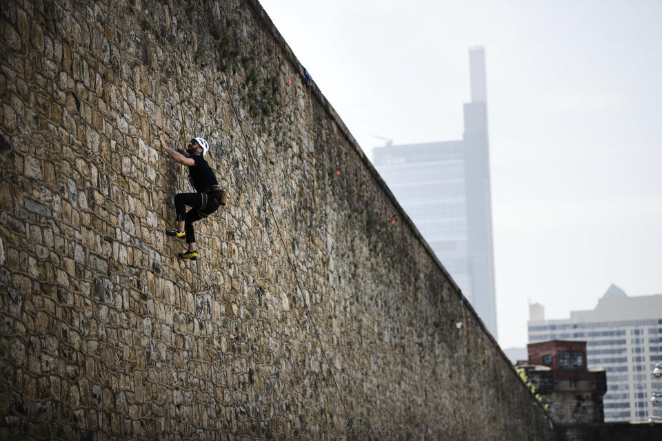Artist Alexander Rosenberg scales a wall of the Eastern State Penitentiary, Thursday, May 2, 2019, which is now a museum in Philadelphia, as part of his project titled "A Climber's Guide to Eastern State Penitentiary or, Eastern State's Architecture, and How to Escape It." (AP Photo/Matt Rourke)