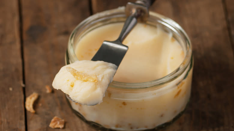 Jar of rendered goose fat, spatula of fat resting across top