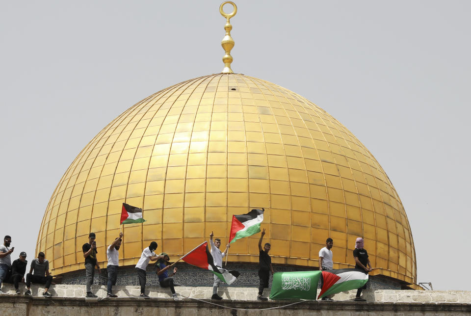 FILE - In this Friday, May 21, 2021 file photo, Palestinians wave national and Hamas flags in front of the Dome of the Rock shrine at the al-Aqsa mosque complex in Jerusalem. The U.S. and the international community are planning to engage with the Palestinians to revive peace efforts, after weeks of unrest and a devastating 11-day war in Gaza. But when U.S. Secretary of State Antony Blinken visits this week, he will meet with unelected leaders who were sidelined by the protests and outmaneuvered by Gaza's militant Hamas rulers. (AP Photo/Mahmoud Illean, File)