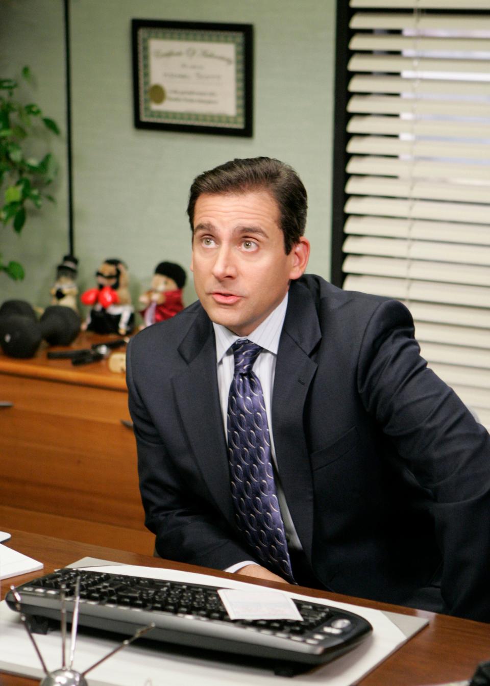 Man in office with a suit and tie, looking surprised, toys on shelf behind him