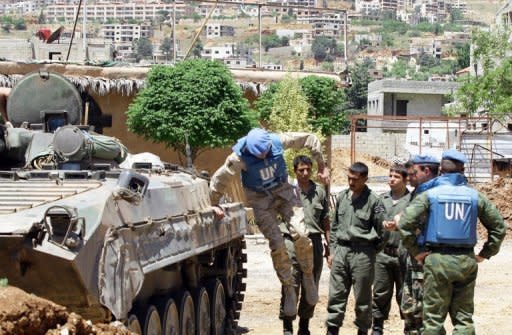 A UN monitor jumps off a tank during a visit to a military outpost at the entrance of the Syrian city of Zabadani. Syria's authorities and the opposition traded accusations Sunday over who was behind blasts that rocked Damascus and Aleppo, on the eve of parliamentary polls designed to boost the regime's legitimacy