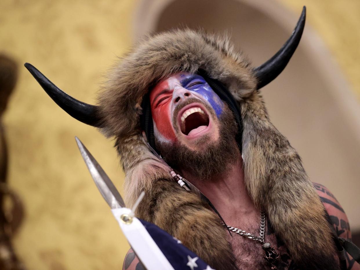 Jacob Chansley waving an American flag while shouting during the Capitol riots.