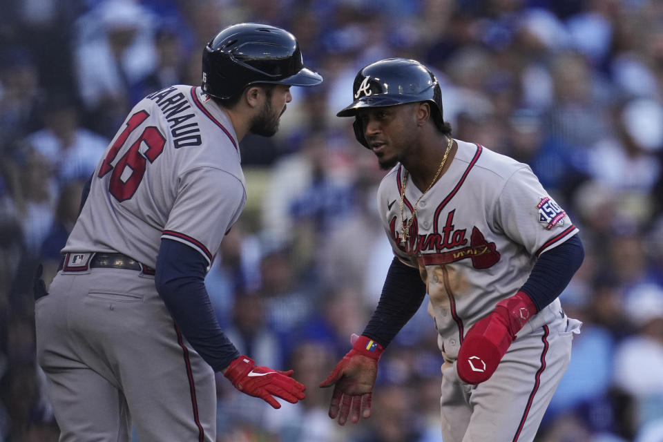 Atlanta Braves' Ozzie Albies celebrates with Braves' Travis d'Arnaud (16) after scoring on an RBI single by Adam Duvall in the fifth inning against the Los Angeles Dodgers in Game 3 of baseball's National League Championship Series Tuesday, Oct. 19, 2021, in Los Angeles. (AP Photo/Ashley Landis)