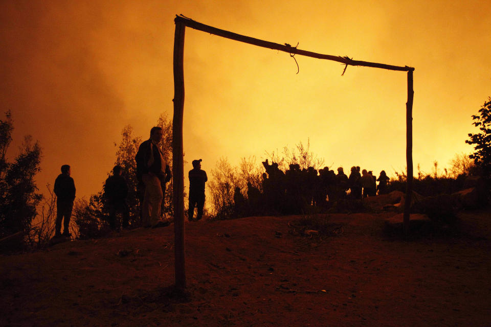 People watch as a forest fire destroys homes in Valparaiso, Chile, Sunday April 13, 2014. Authorities say the fires have destroyed hundreds of homes, forced the evacuation of thousands and claimed the lives of at least seven people. ( AP Photo/ Luis Hidalgo)