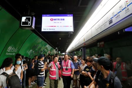 Mass Transit Railway (MTR) personnel walk under a sign reading "Not in Service" as train services are suspended following a disruption by protesters at Fortress Hill station in Hong Kong