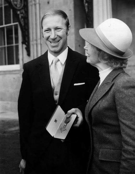 Charlton, with his wife Pat, displays his OBE outside Buckingham Palace in 1974 (Getty)