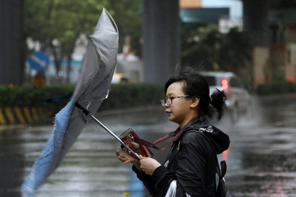 A woman struggles against gusts of wind generated by Typhoon Mitag in Taipei, Taiwan, Monday, Sept. 30, 2019. Fast-moving Typhoon Mitag was bearing down on northern Taiwan on Monday, bringing high winds and heavy rain and forcing flight cancellations. (AP Photo/Chiang Ying-ying)