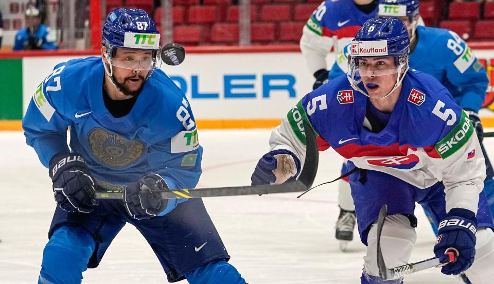 Slovakia's Simon Nemec, right, and Adil Beketayev from Kazakhstan, left, challenge for the puck during the group A Hockey World Championship match between Kazakhstan and Slovakia in Helsinki, Finland, Friday May 20 2022. (AP Photo/Martin Meissner)