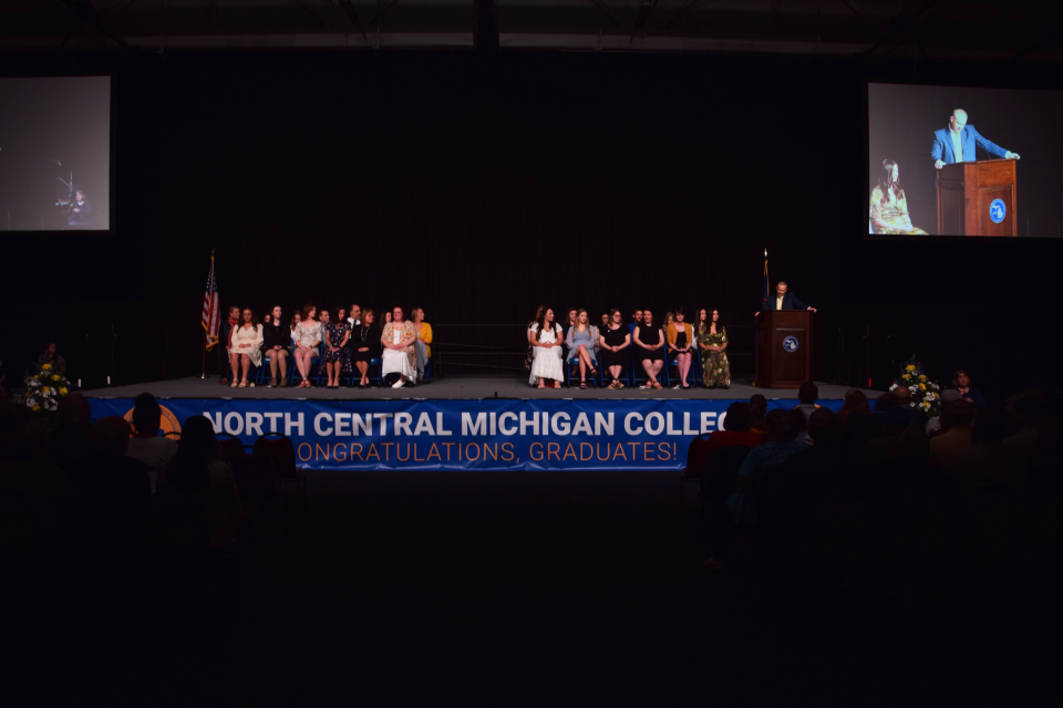 North Central Michigan College nursing graduates sit on the stage and listen to the speaker during the 2023 Nurse Pinning ceremony.