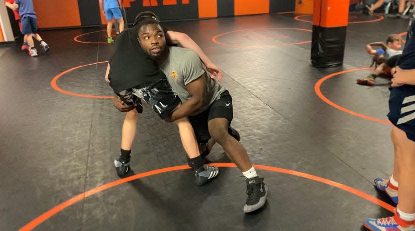 Cathedral Prep alumnus and Iowa State wrestler Paniro Johnson demonstrates a wrestling move at Tuesday’s Rambler Wrestling Club practice.