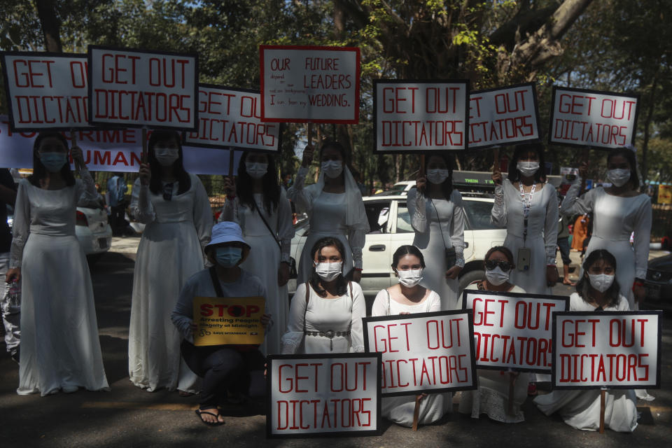 Anti-coup protesters hold placards reading "Get out dictators" outside the U.N. Information Office in Yangon, Myanmar, Sunday, Feb. 14, 2021. Vast numbers of people all over Myanmar have flouted orders against demonstrations to march again in protest against the military takeover that ousted the elected government of Suu Kyi. (AP Photo)